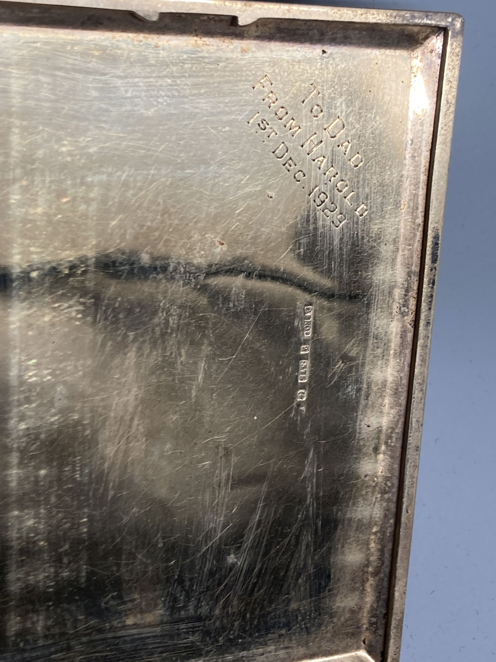 A late 1920s 9ct gold engine-turned cigarette case, with chased fleur-de-lys border, inscribed to interior, 11.3cm, gross 141g,